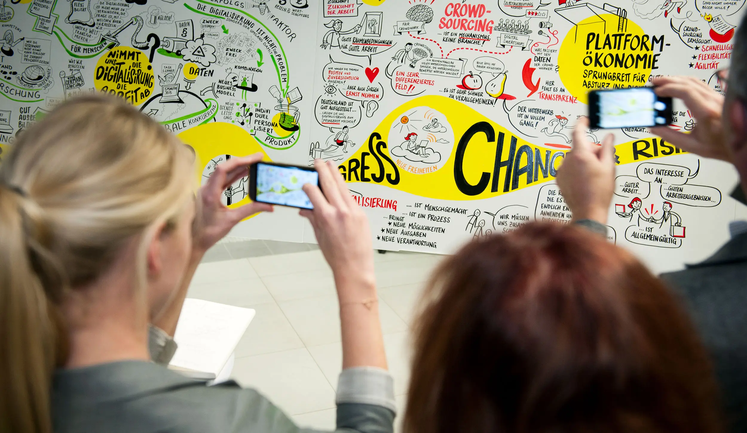 Teilnehmende fotografieren Michael Schrenks Graphic Recording auf einer Veranstaltung